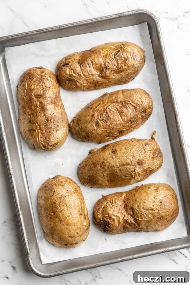 Crisp up the skins. Overhead view of upside down potato halves on parchment-lined baking sheet
