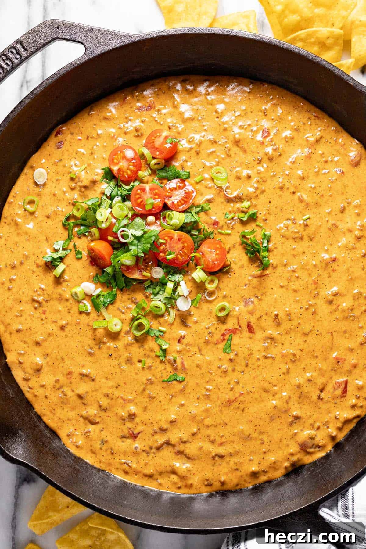 Creamy Rotel Dip Recipe with Cheesy Sausage for Parties 8 Cast iron skillet filled with Velveeta dip garnished with tomatoes, cilantro, and sliced green onion.