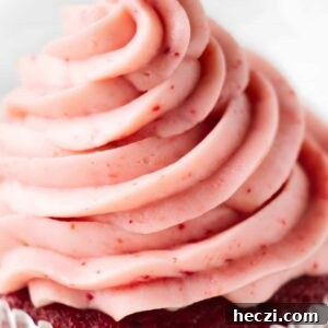 Strawberry Cream Cheese Frosting Recipe for Cakes & Cupcakes 6 Close-up of a cupcake with pink swirled frosting in white liner.