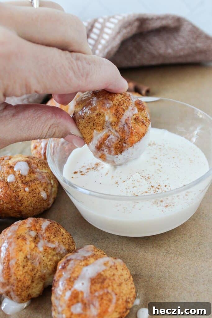 Air Fryer Cinnamon Roll Bites Made with 2-Ingredient Dough 11 An air fryer cinnamon roll bite being dipped into Greek yogurt dip.