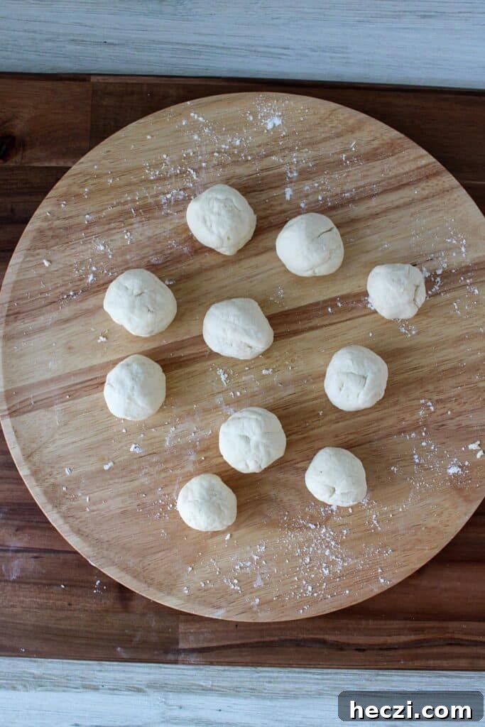 Air Fryer Cinnamon Roll Bites Made with 2-Ingredient Dough 6 Two ingredient dough rolled in balls on a wooden board.