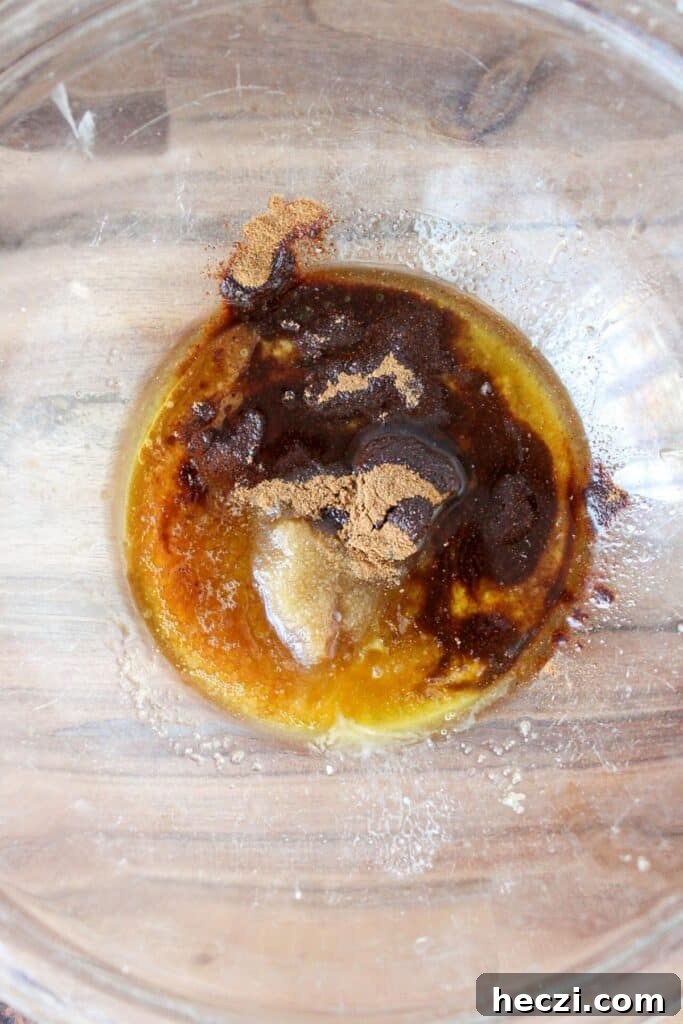 Air Fryer Cinnamon Roll Bites Made with 2-Ingredient Dough 7 A clear bowl with melted butter, brown sugar, maple syrup, cinnamon and vanilla, unmixed.
