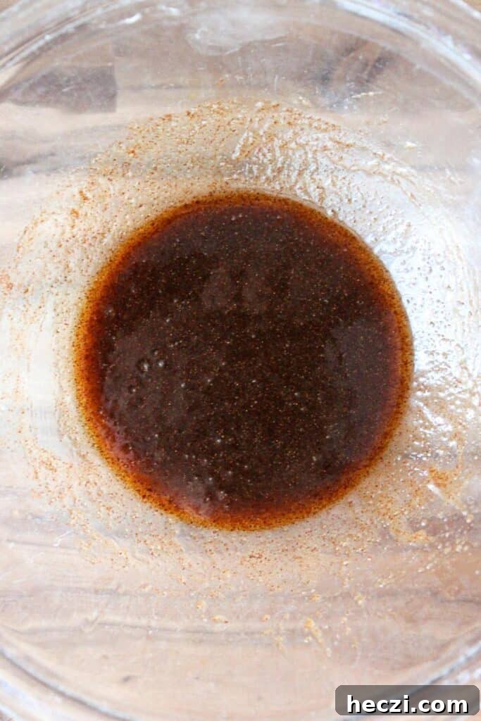 Air Fryer Cinnamon Roll Bites Made with 2-Ingredient Dough 8 A clear bowl of melted butter, maple syrup, cinnamon, brown sugar, and vanilla mixed.