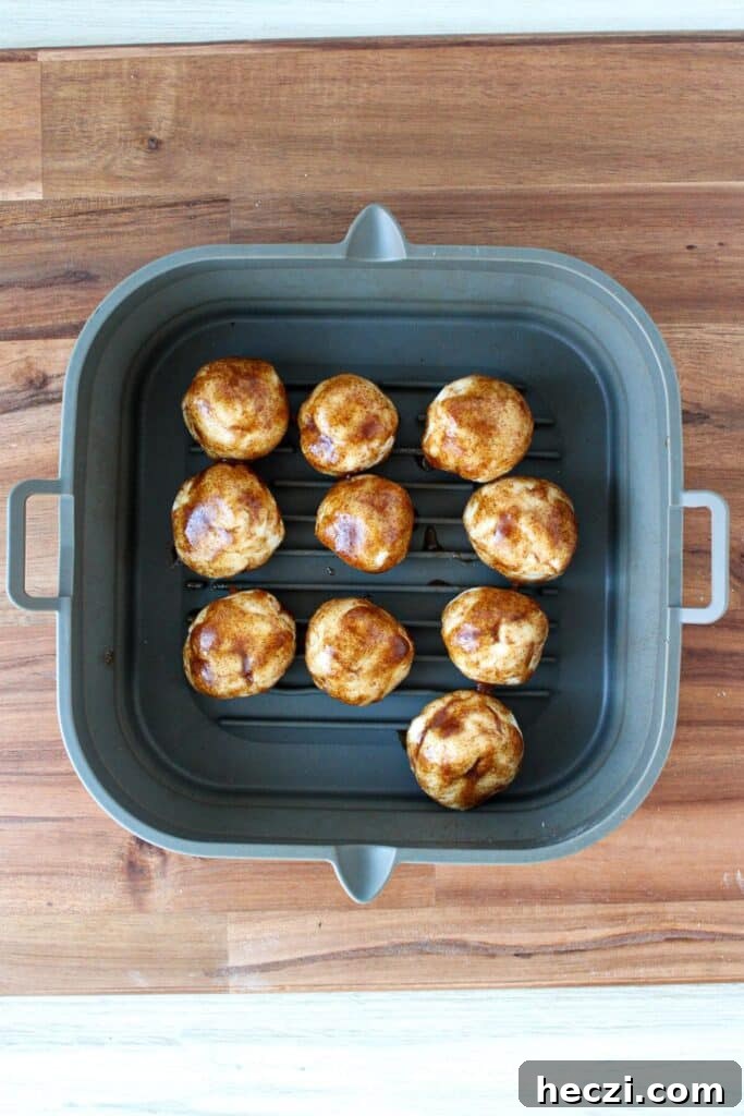 Air Fryer Cinnamon Roll Bites Made with 2-Ingredient Dough 9 Two ingredient dough balls coated with a melted butter, cinnamon and sugar mixture in a silicone air fryer tray.