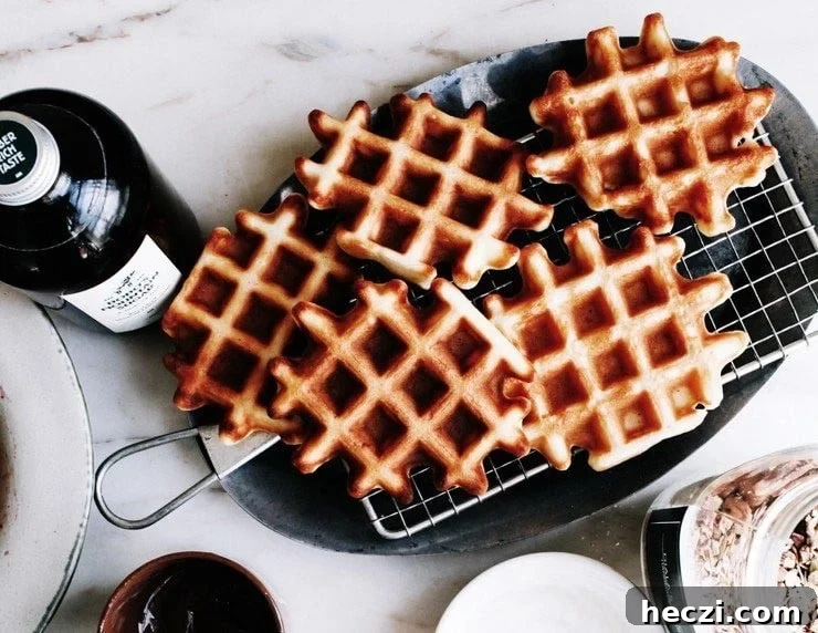 Classic Homemade Belgian Waffles Recipe for Crispy, Fluffy Results 8 Homemade Belgian waffles on a platter with maple syrup on the side.