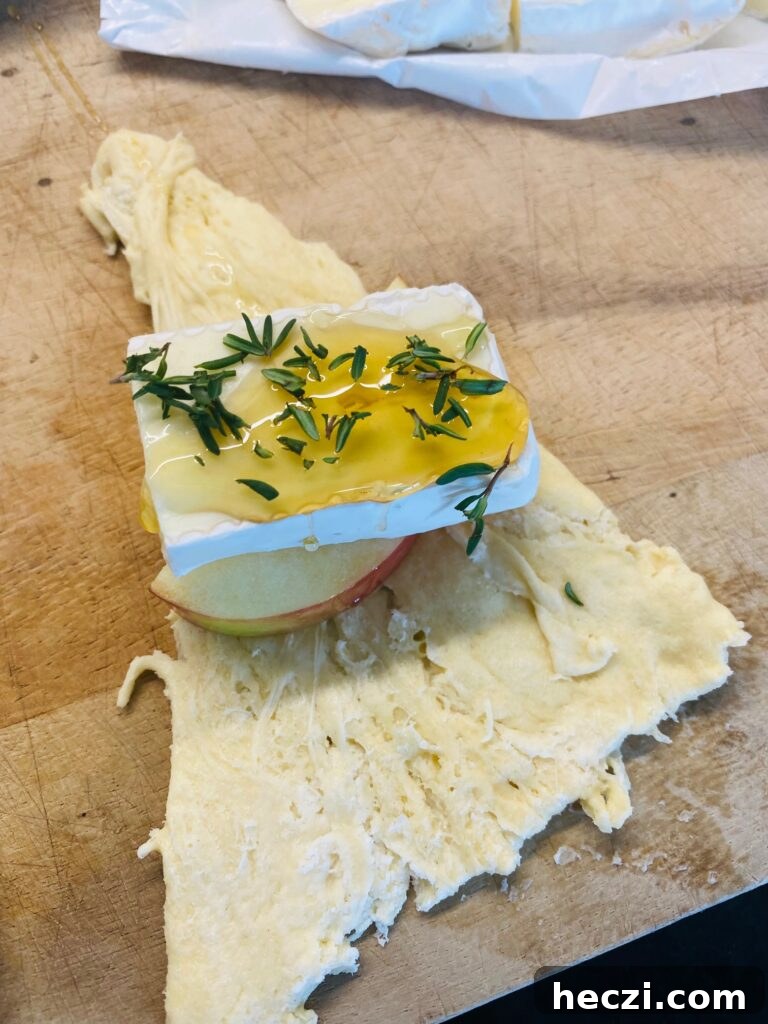 Crispy Apple and Brie Roll-Ups with Honey Dijon Dip 5 adding fresh thyme leaves over the honey and cheese