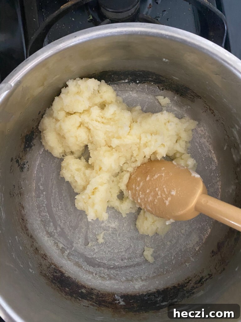 Turn the heat back on to a very very very low temperature and continue cooking the flour panade for one minute. Make sure to keep string the dough ball. It will form a film on the bottom of the pan.
