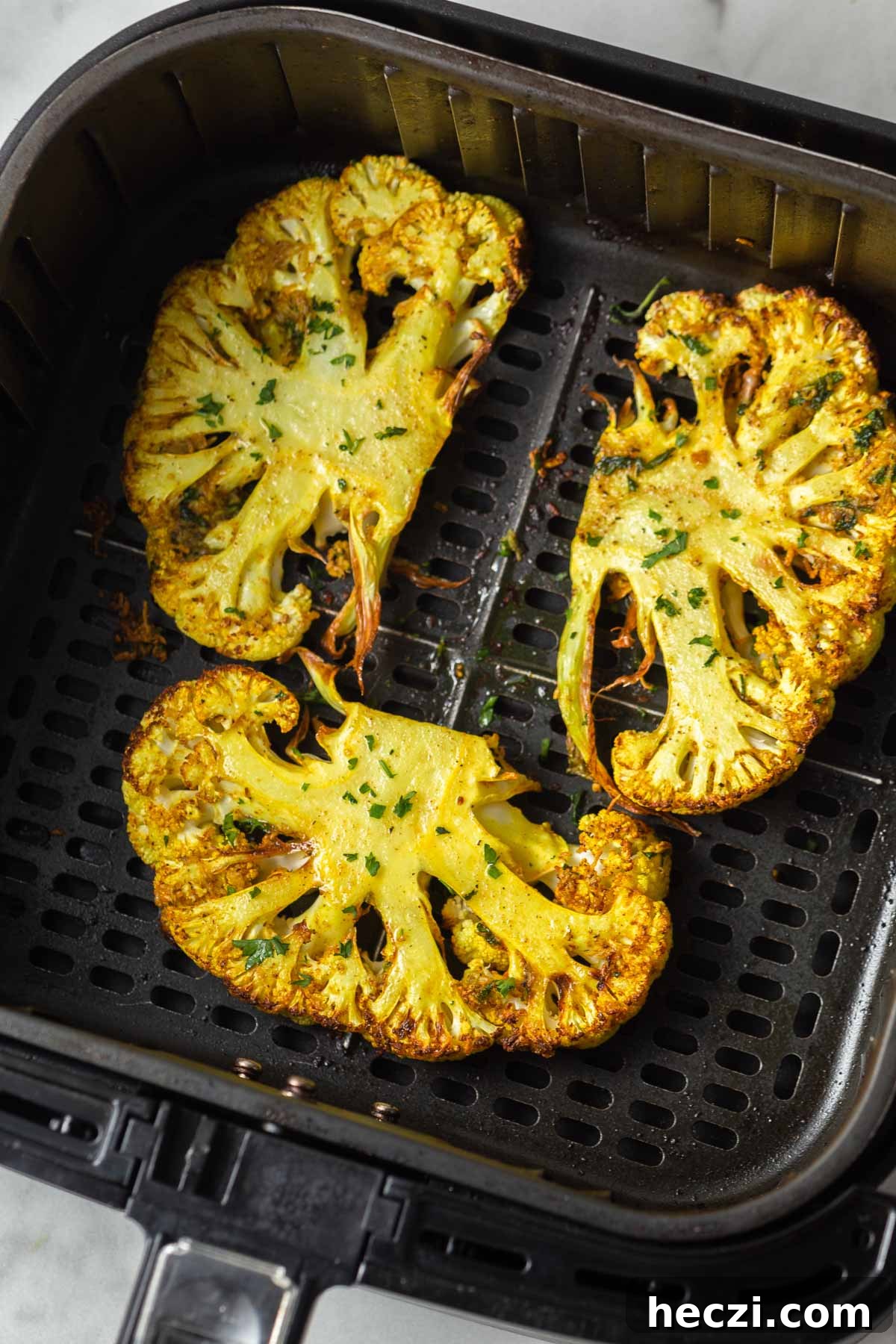 air fried cauliflower steaks in the air fryer basket.