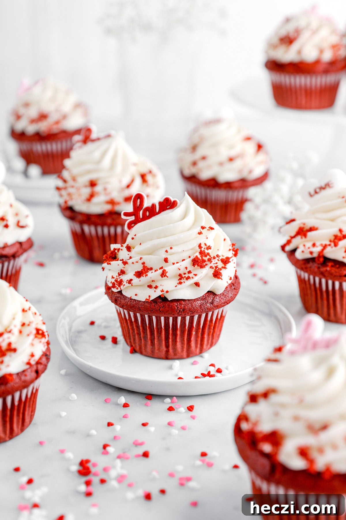 Red Velvet Molten Lava Cupcakes: Gooey Chocolate Center Delight 11 A close-up of a red velvet cupcake with a swirl of creamy white frosting, garnished with red velvet crumbs. A small red topper spelling 'Love' sits atop the frosting.