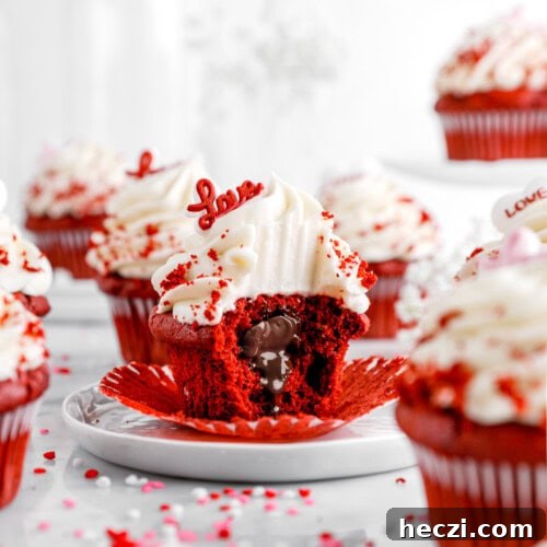 Red Velvet Molten Lava Cupcakes: Gooey Chocolate Center Delight 12 A red velvet cupcake with cream cheese frosting and red velvet crumbs sits on a white plate, its wrapper peeled back. A bite reveals a gooey, molten chocolate center. A red