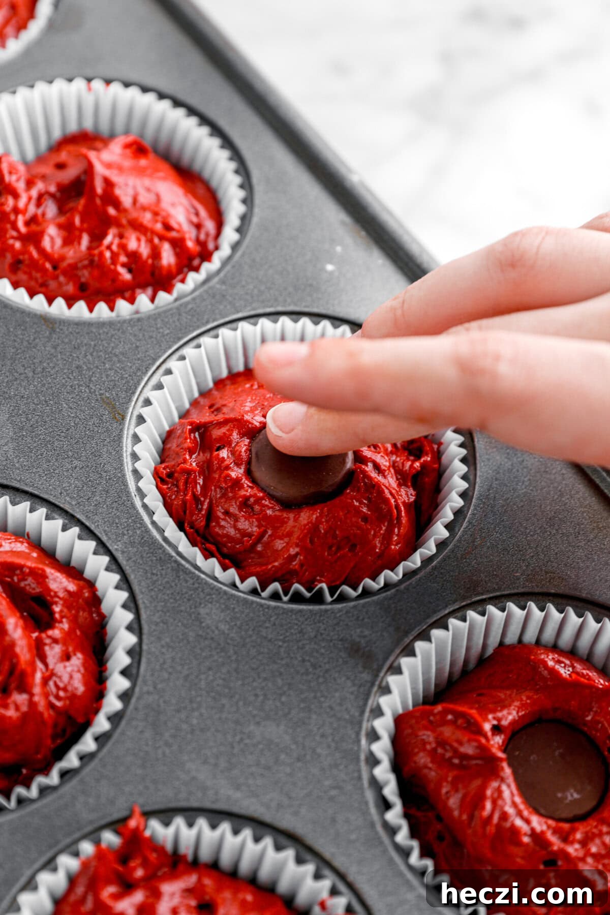 Red Velvet Molten Lava Cupcakes: Gooey Chocolate Center Delight 8 chocolate being placed in the center of cupcake.