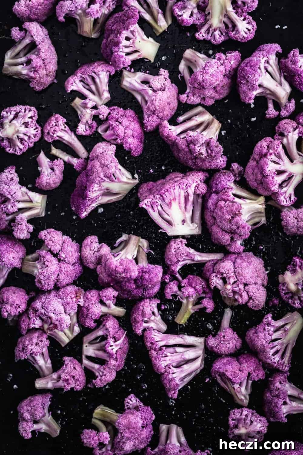 Cut up raw cauliflower on a sheet pan with salt about to go in the oven.
