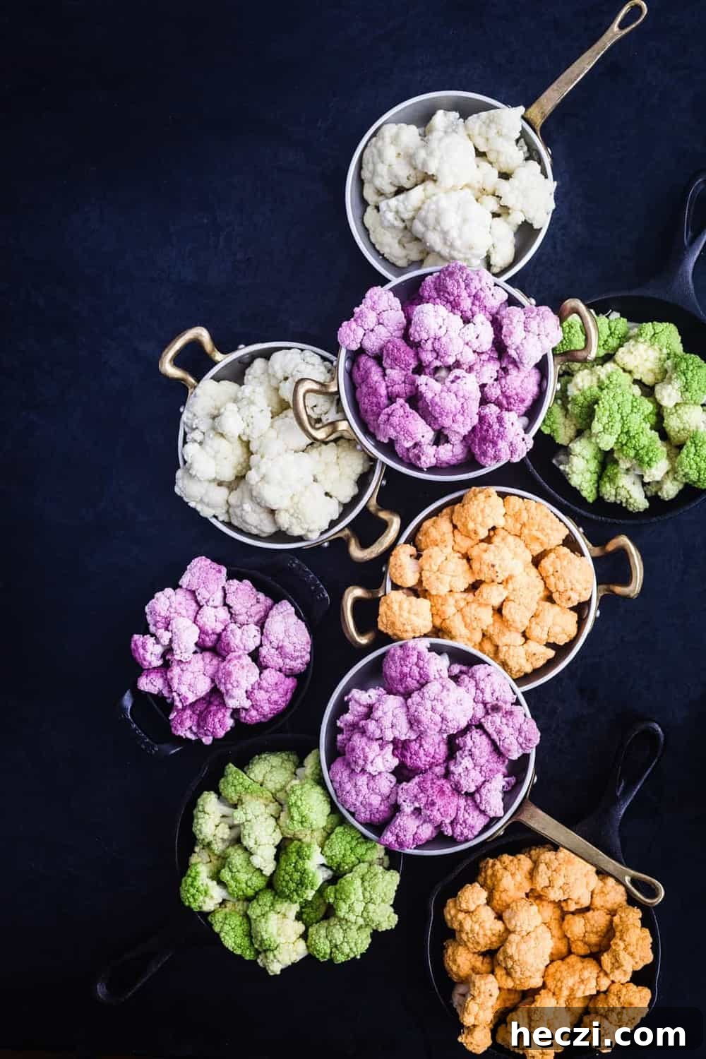 Rainbow cauliflower shot with purple, yellow/orange/green and white cauliflower cut up in little pans.