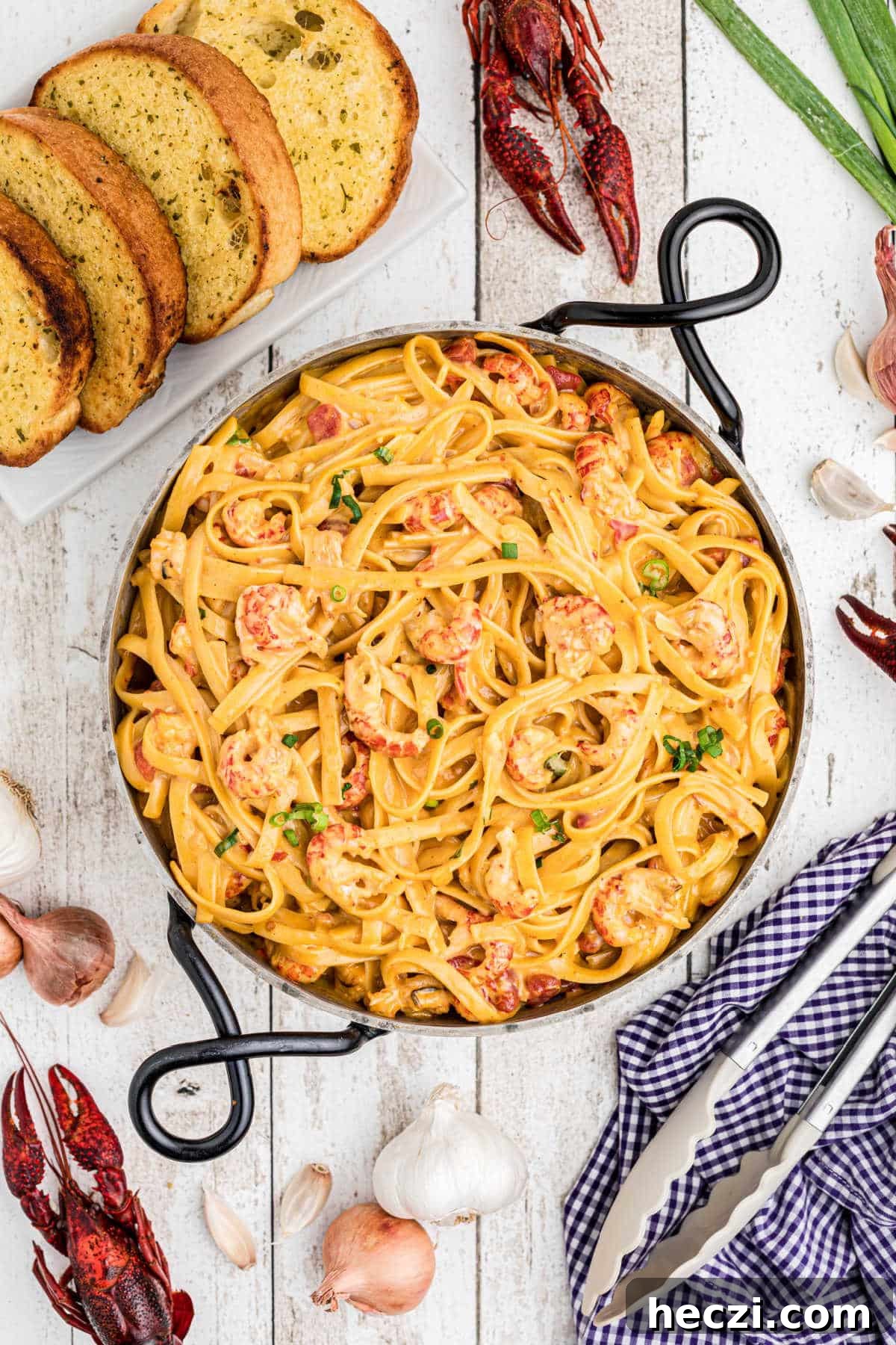 Creamy Crawfish Fettuccine with Garlic and Parmesan 14 overhead view of crawfish fettuccine in a skillet with boiled crawfish and garlic and texas toast arranged around