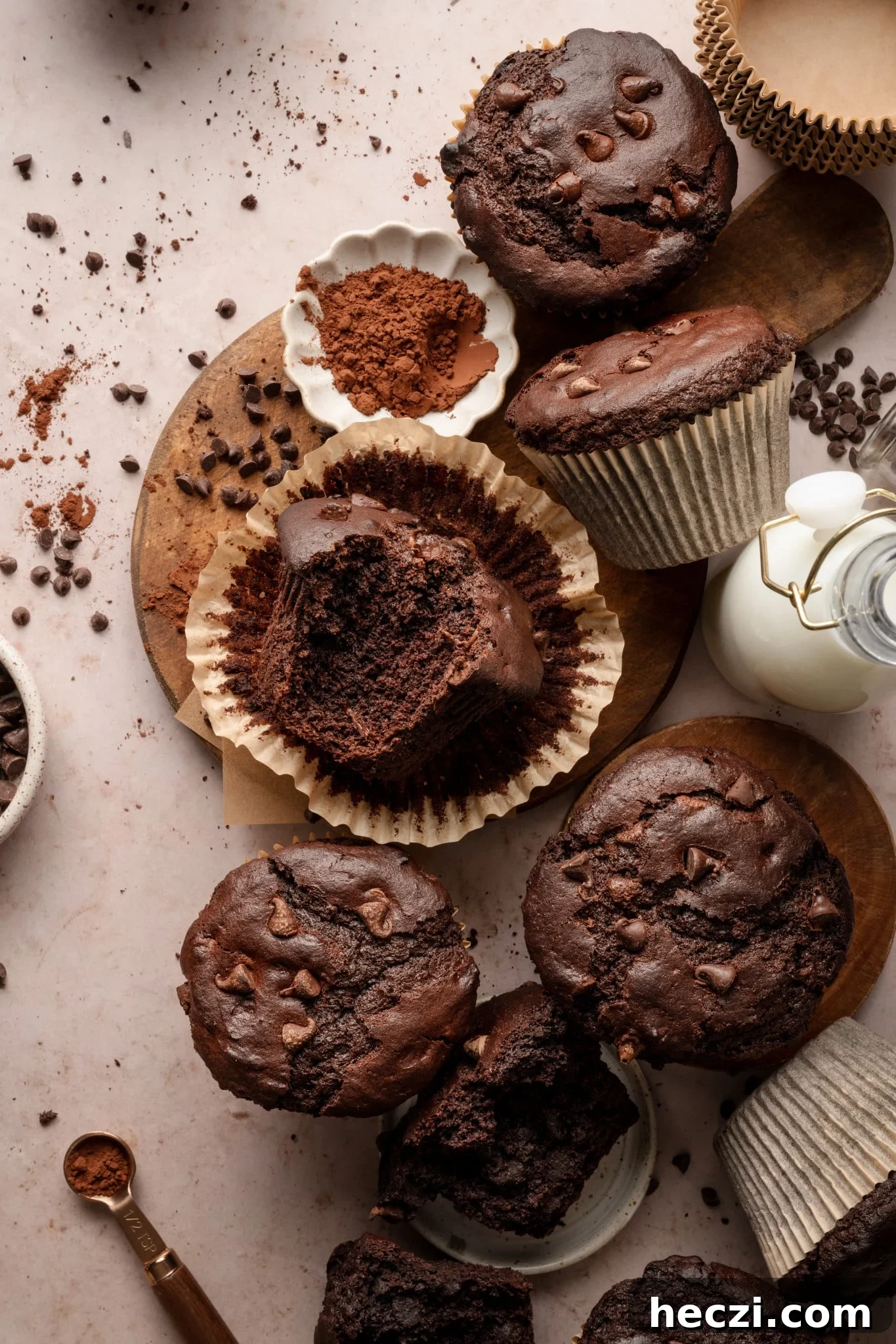 Costco-Style Double Chocolate Muffins Recipe (Copycat) 2 Copycat costco double chocolate muffins on top of counter top with buttermilk and cocoa powder on board. One of the muffins is unwrapped from paper liner and bite taken out of the center.