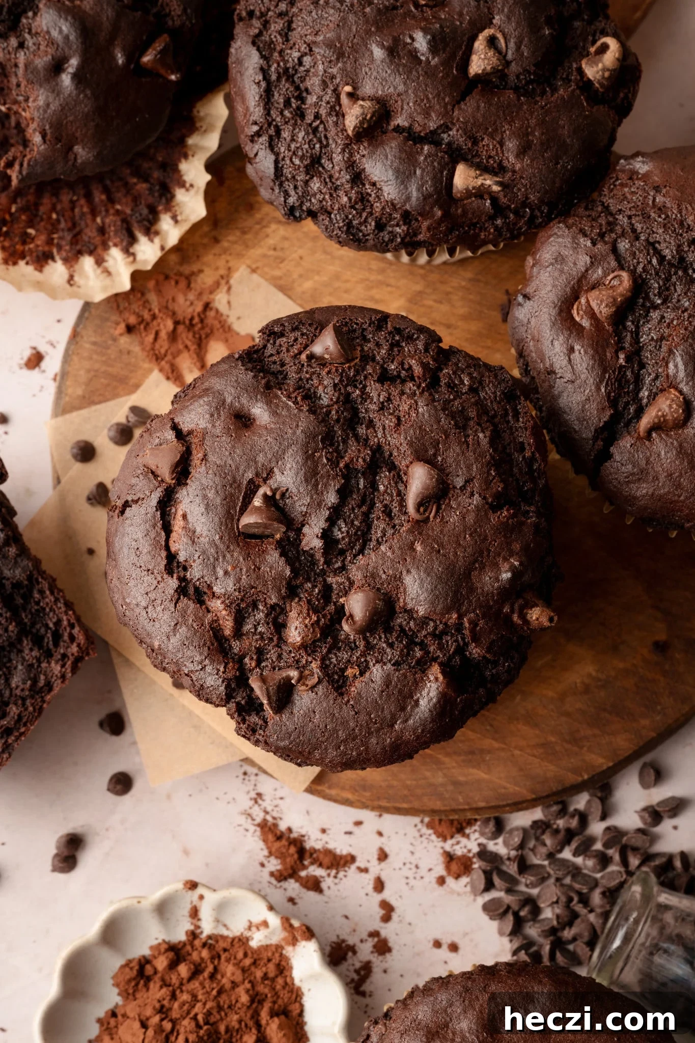 Costco-Style Double Chocolate Muffins Recipe (Copycat) 4 Aerial shot of the top of oversized, jumbo chocolate muffin on wood board with remaining muffins surrounding it.