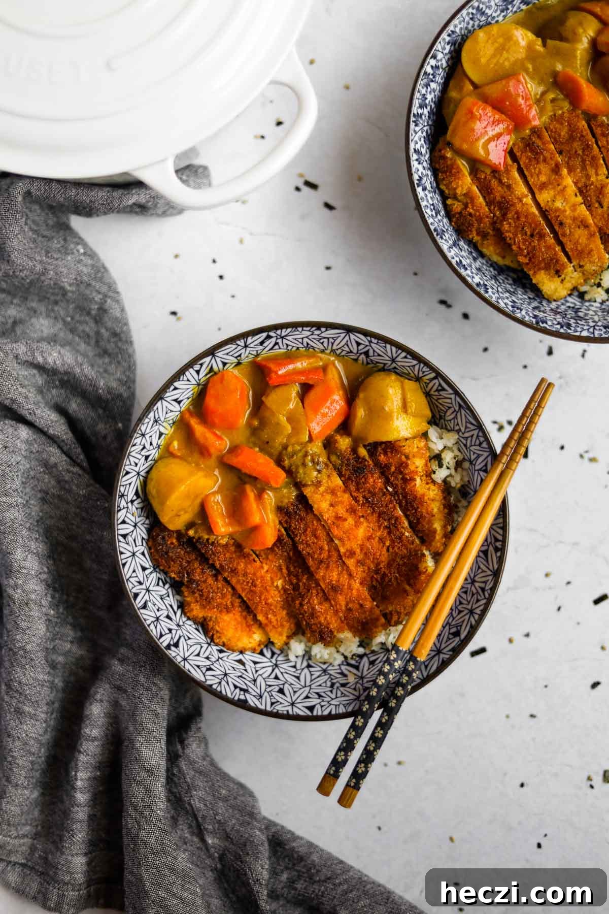 Japanese Chicken Katsu Curry Recipe — Crispy Cutlet with Rich Curry 2 Overhead shot of Chicken Katsu Curry in a blue Japanese porcelain bowl with blue and wood bamboo chopsticks and a white Le Creuset dutch oven
