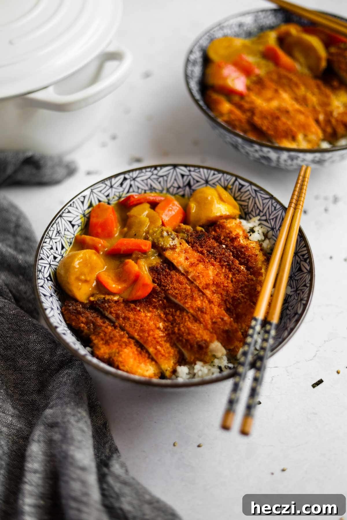 Japanese Chicken Katsu Curry Recipe — Crispy Cutlet with Rich Curry 11 Chicken Katsu Curry in a blue Japanese porcelain bowl with blue and wood bamboo chopsticks and a white Le Creuset dutch oven