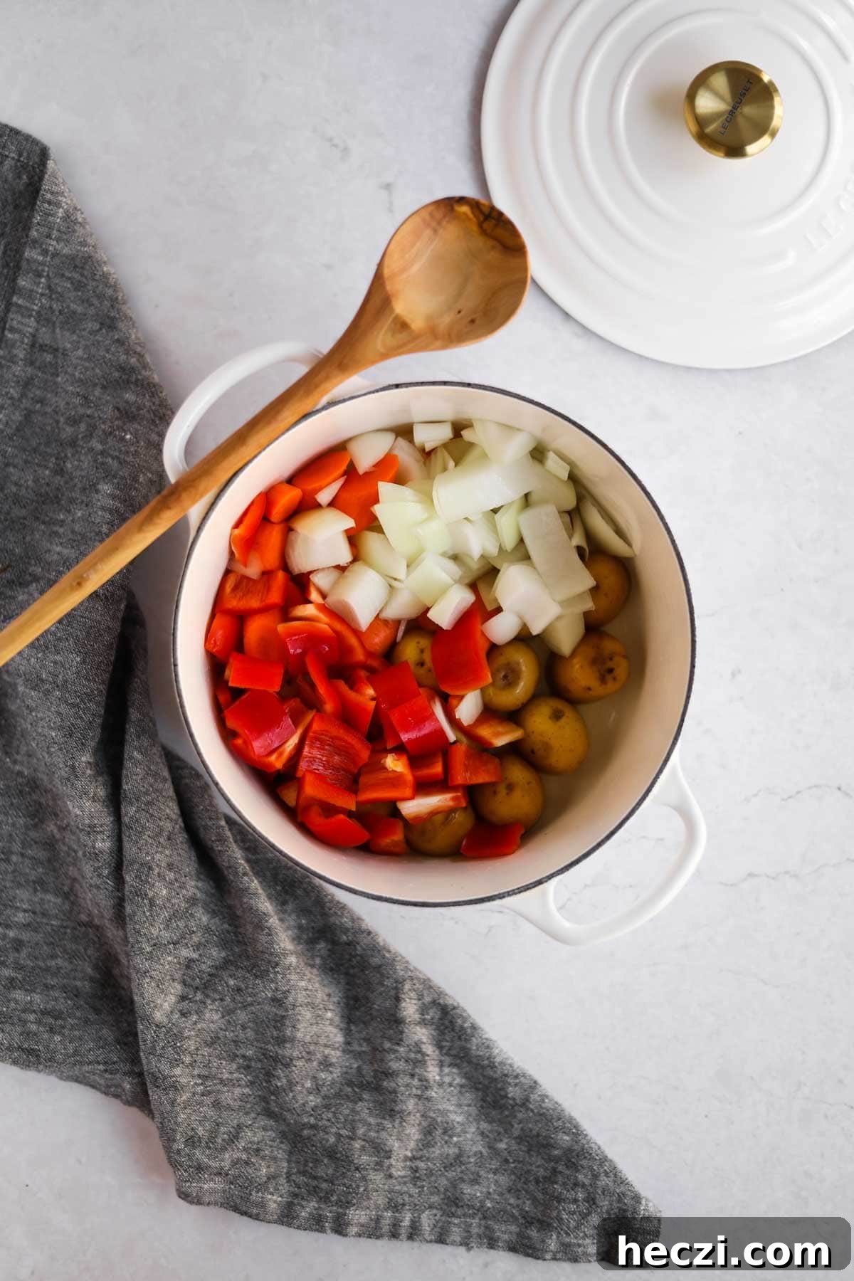 Japanese Chicken Katsu Curry Recipe — Crispy Cutlet with Rich Curry 5 Overhead shot of onion, potatoes, bell peppers in white Le Creuset dutch oven with wooden spoon