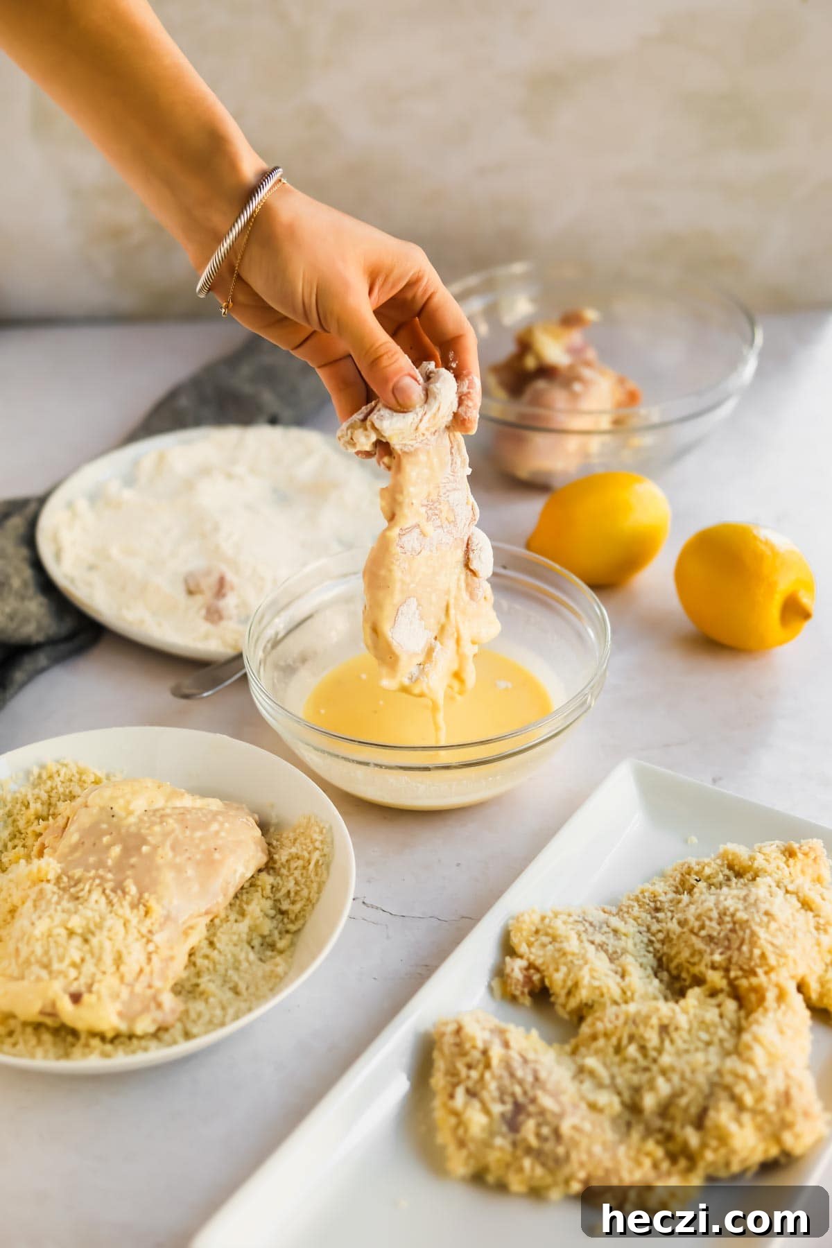 Japanese Chicken Katsu Curry Recipe — Crispy Cutlet with Rich Curry 9 Raw chicken being dipped into egg mixture with lemons, flour, and panko