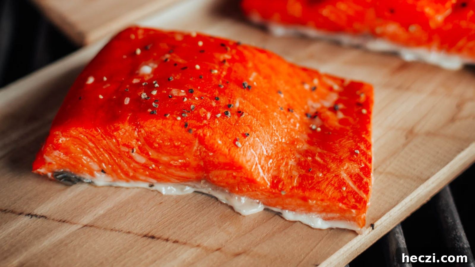 Smoked cedar plank salmon with rich smoky color and lemon slices resting on the plank.