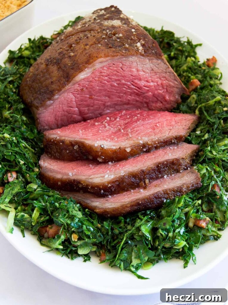 Perfect Picanha Roast Recipe for Juicy, Crispy Crust 9 close up of a sliced Picanha Roast on sauteed greens