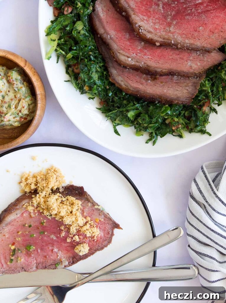 Perfect Picanha Roast Recipe for Juicy, Crispy Crust 10 a plate with a slice of Picanha Roast topped with farofa next to a platter with the rest of the roast and greens