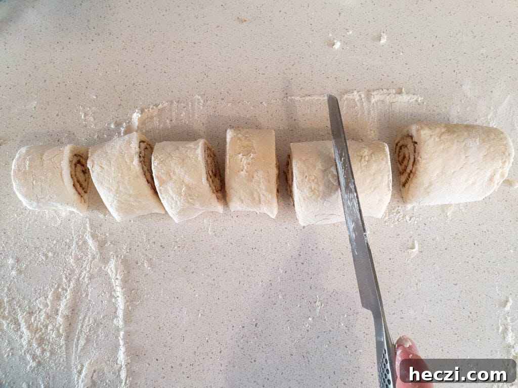 Air Fryer Cinnamon Rolls: Quick, Fluffy Homemade Recipe 11 Slicing up rolls with a sharp knife.