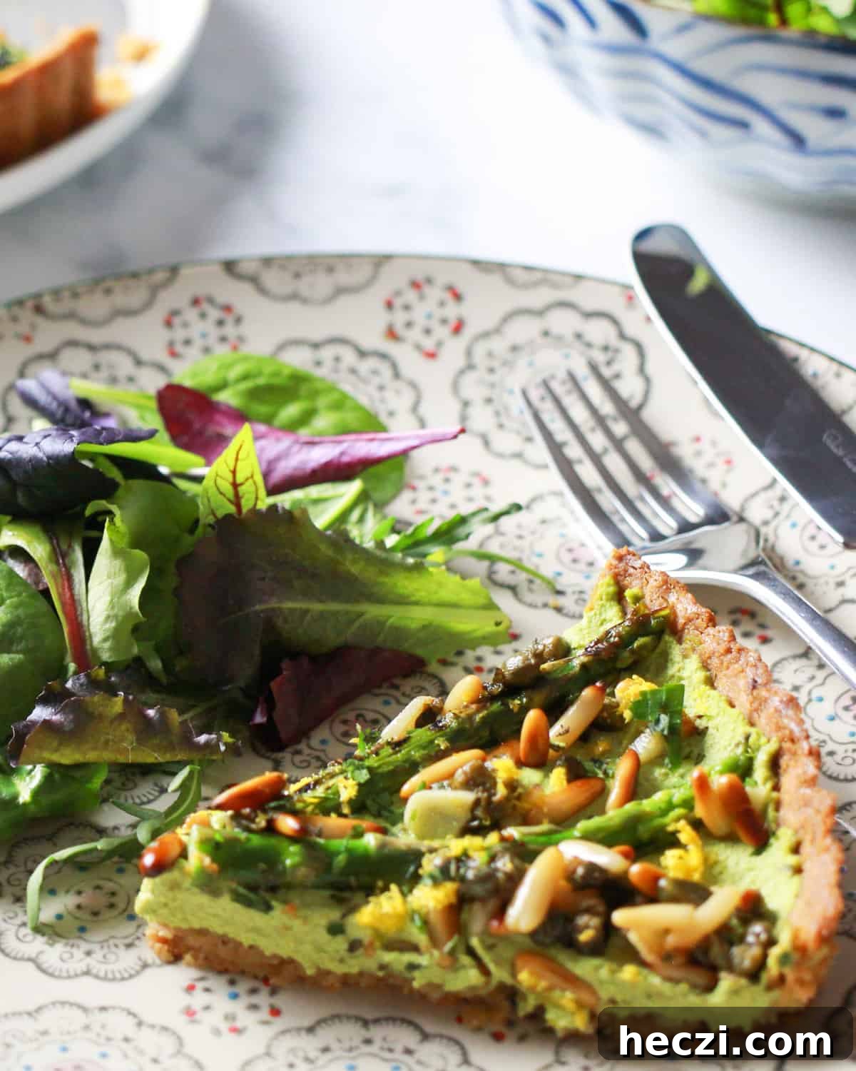 photo of a plate with a slice of vegan asparagus tart and some salad.