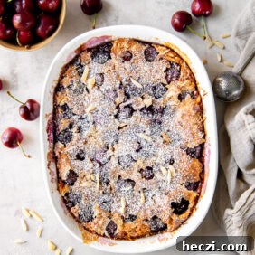baking dish of cherry clafoutis next to bowl of fresh cherries.