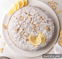 lemon ricotta cake with almonds, confectioners' sugar and lemon wedges as garnish.