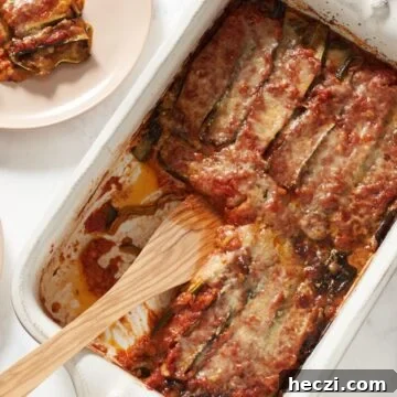 A pan of zucchini parmesan with a wooden spatula in it.