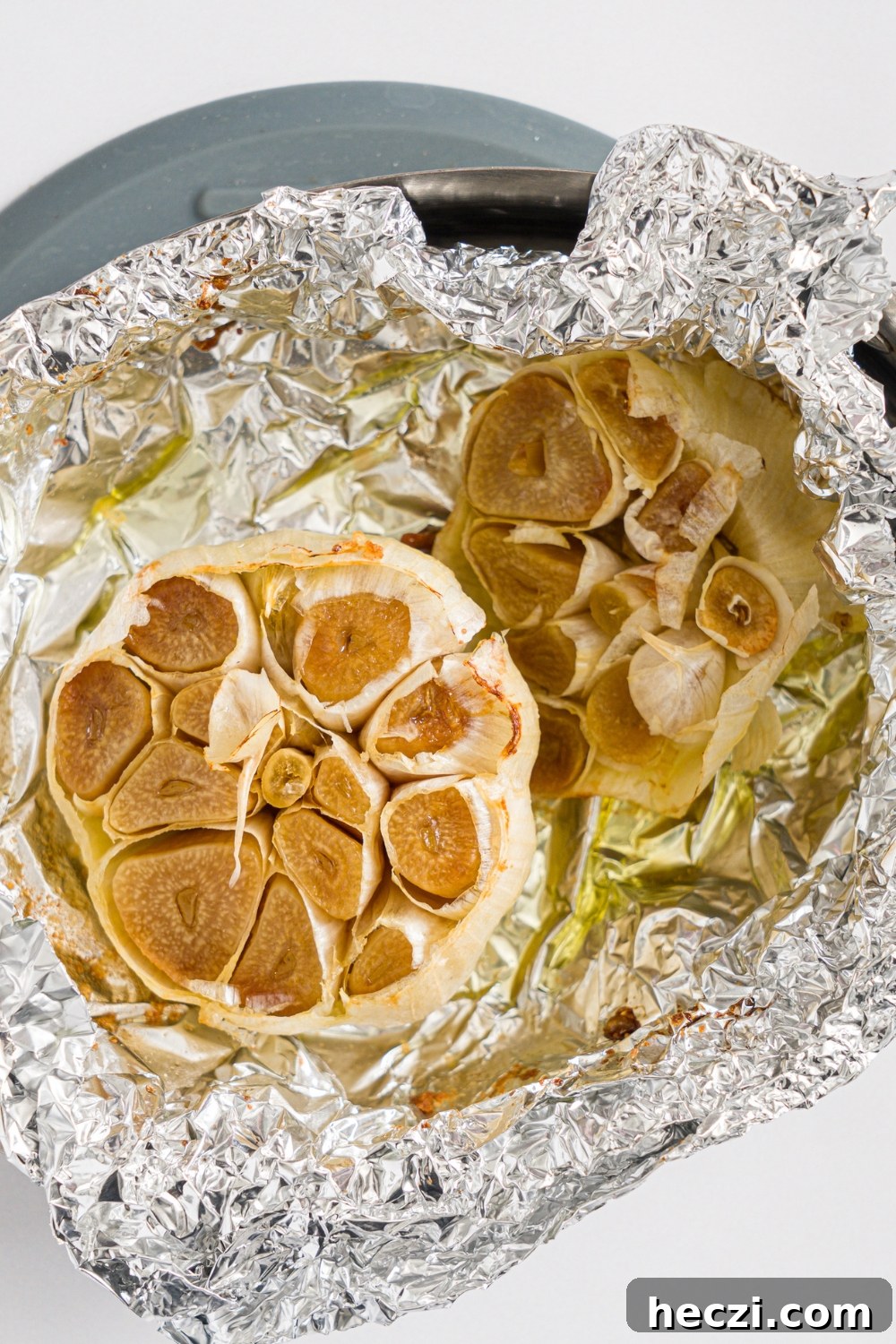 A roasting pan with a garlic bulb drizzled with oil and wrapped in foil.
