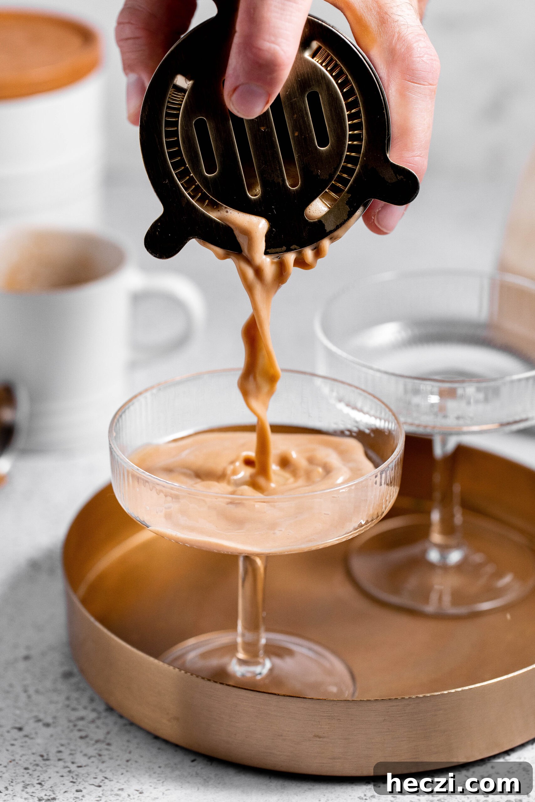 Hand straining espresso martini into a glass. 